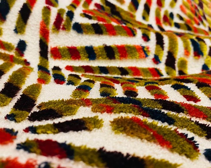 a close up view of an area rug that has been made with different colors and shapes