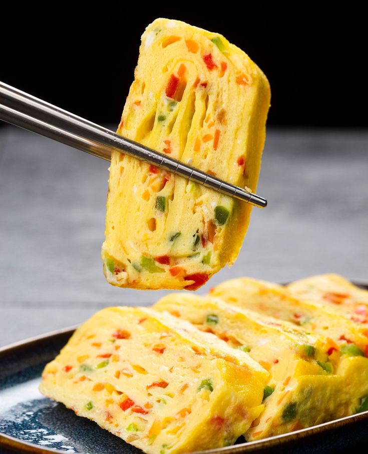 two pieces of omelette being lifted from a plate with tongs over them