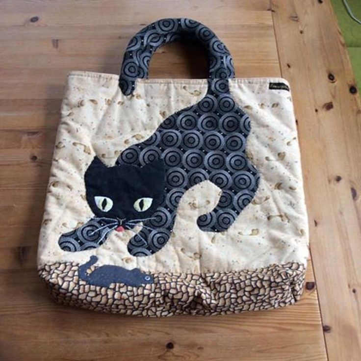 a black cat bag sitting on top of a wooden floor