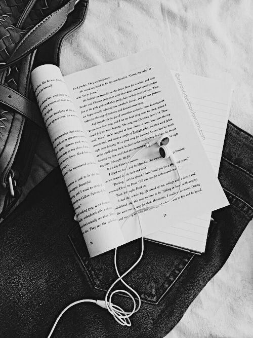 an open book and headphones on top of jeans