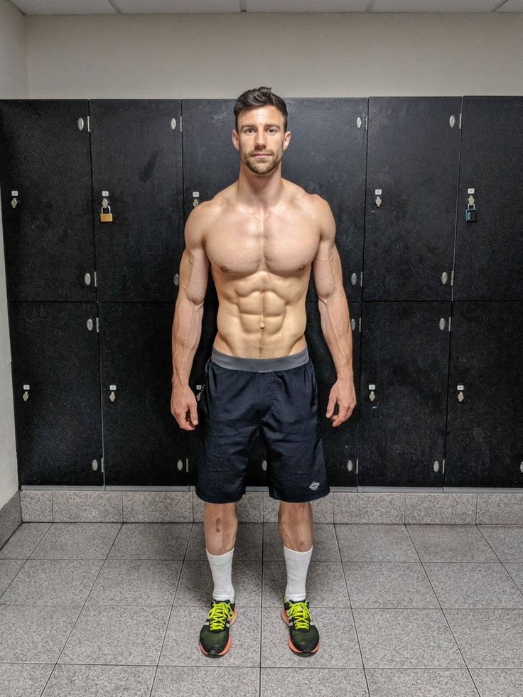 a shirtless man standing in front of lockers with his hands on his hips