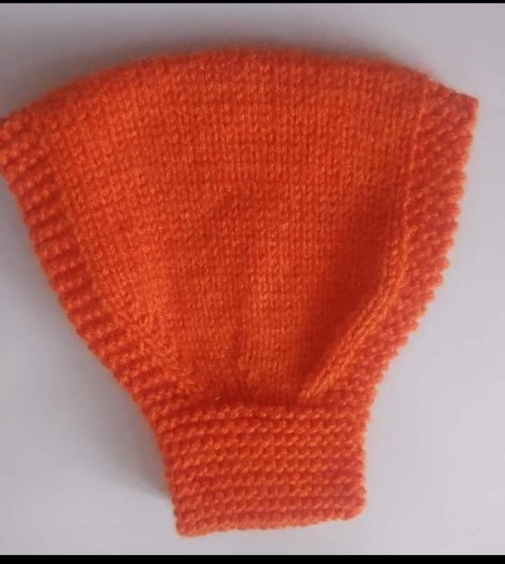 an orange knitted mitten sitting on top of a white table