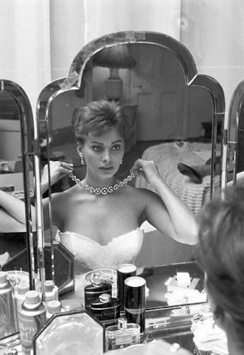 a black and white photo of a woman in front of a mirror looking at herself