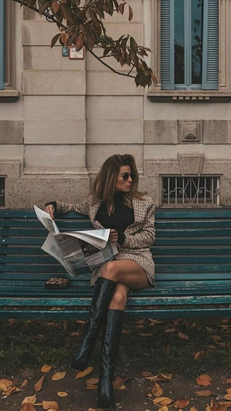 a woman sitting on a bench reading a newspaper