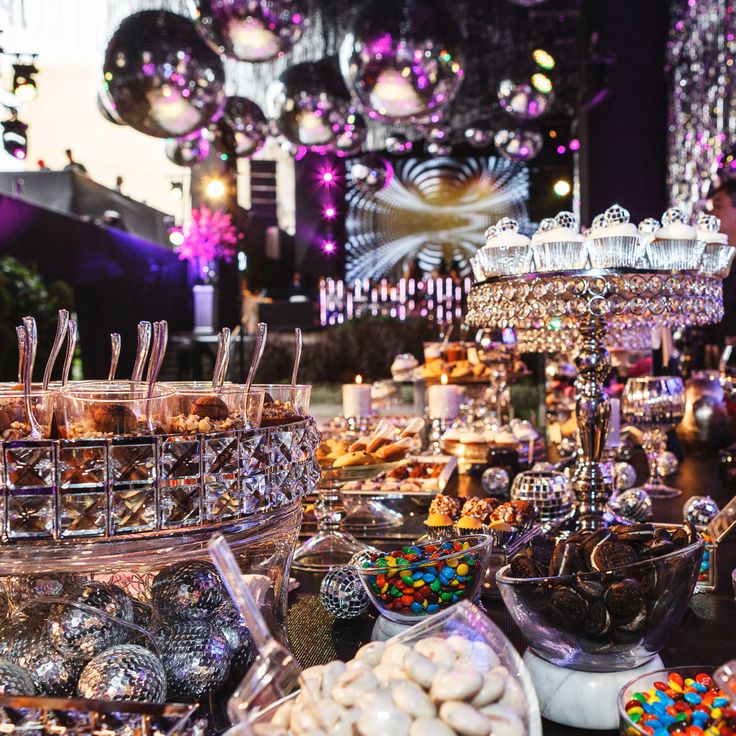 an assortment of desserts and candies on display at a party or event with chandeliers in the background