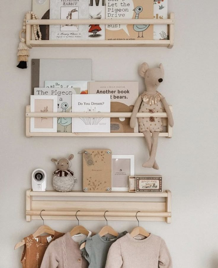 two wooden shelves with clothes hanging on them and a teddy bear in the corner next to it