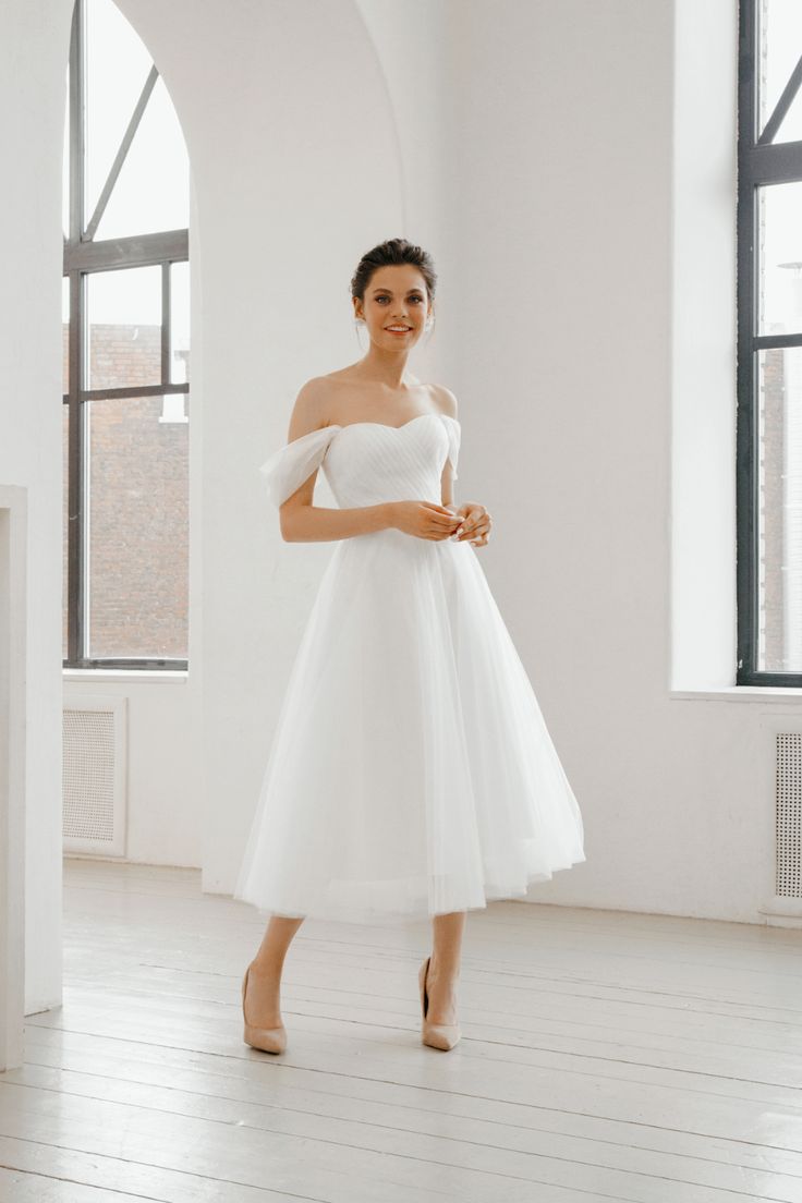 a woman in a white dress posing for the camera with her hands on her hips