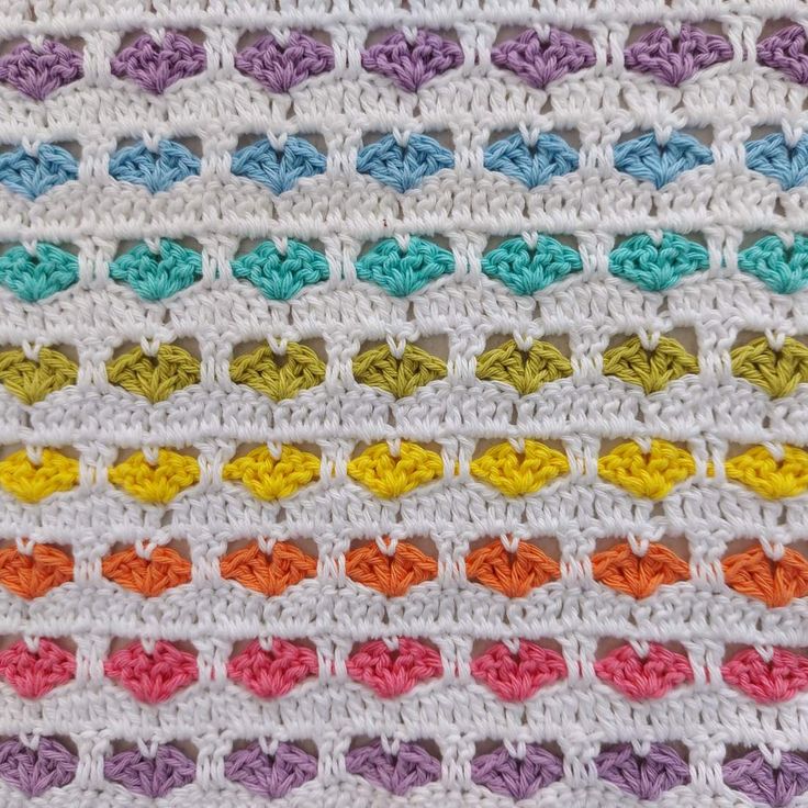 a crocheted blanket with multicolored hearts on the front and back side