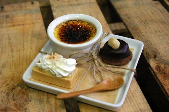 a cup of coffee and some desserts on a plate with a spoon next to it