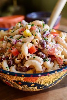 a bowl filled with macaroni salad on top of a wooden table