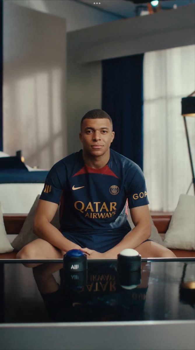 a man sitting on top of a couch next to a coffee table with two cups in front of him