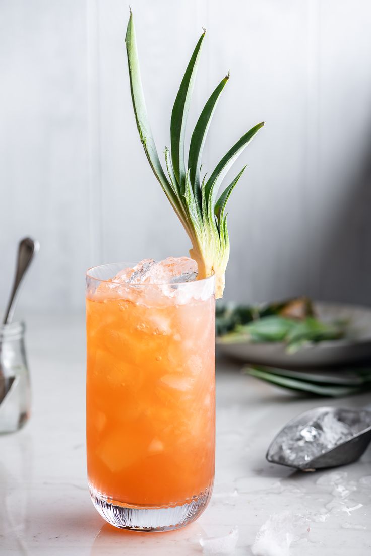 an orange cocktail garnished with a pineapple