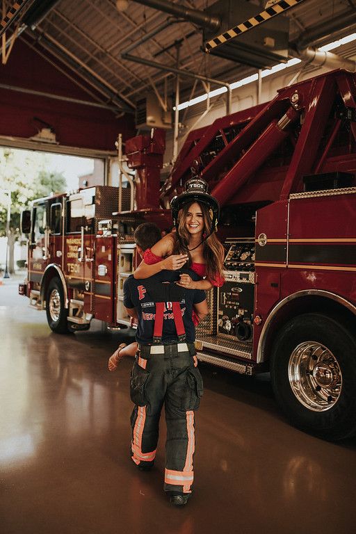 a woman and child are standing in front of a fire truck with their arms around each other