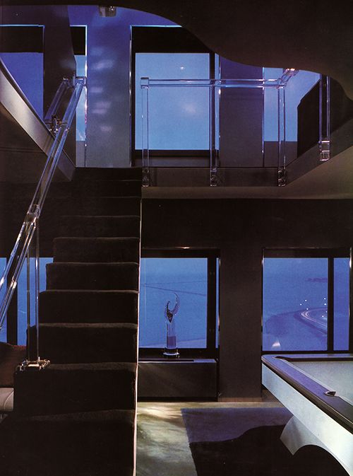 a pool table and some stairs in a room with large windows at the top of it