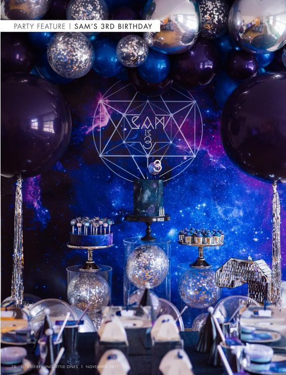 a table topped with lots of purple and silver balloons next to other items in front of a wall