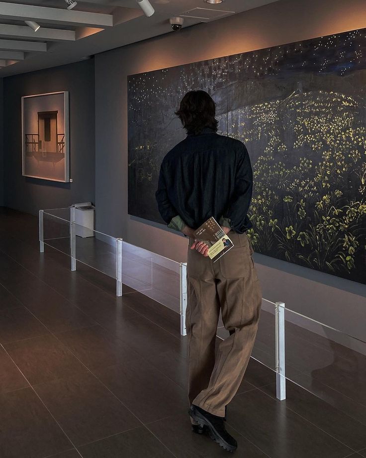 a man standing in front of a painting on display at an art gallery with his back to the camera