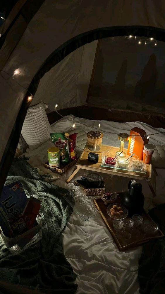 the inside of a tent with food and drinks on it, lit up by string lights