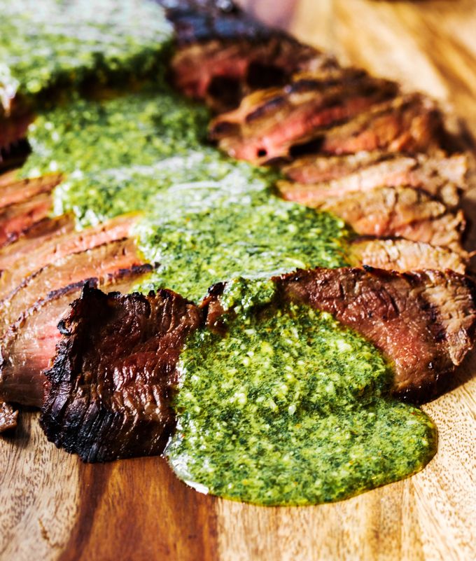 steak with pesto on it sitting on a cutting board