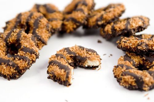 chocolate covered cookies with coconut flakes are arranged on a white surface and have been cut in half