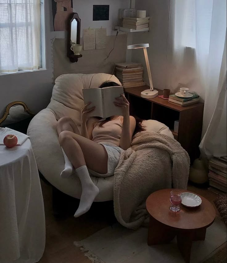 a woman sitting in a chair with a book on top of her head while reading