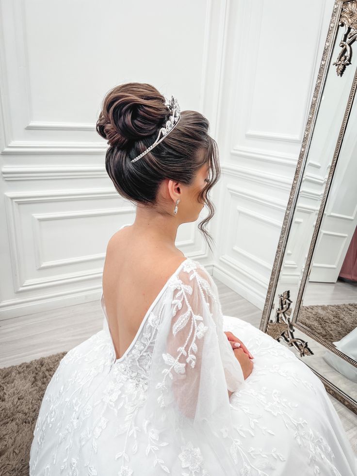 a woman sitting in front of a mirror wearing a wedding dress