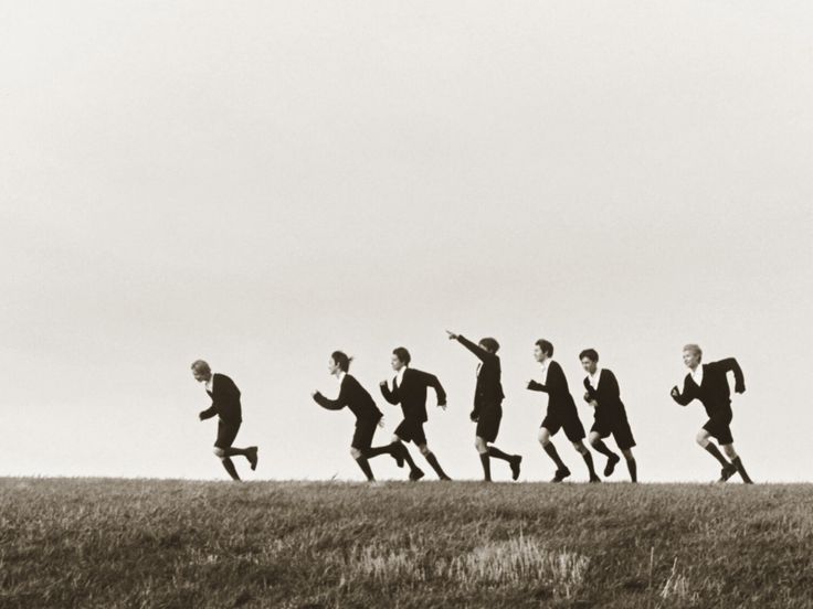 a group of people running across a grass covered field in the middle of a line