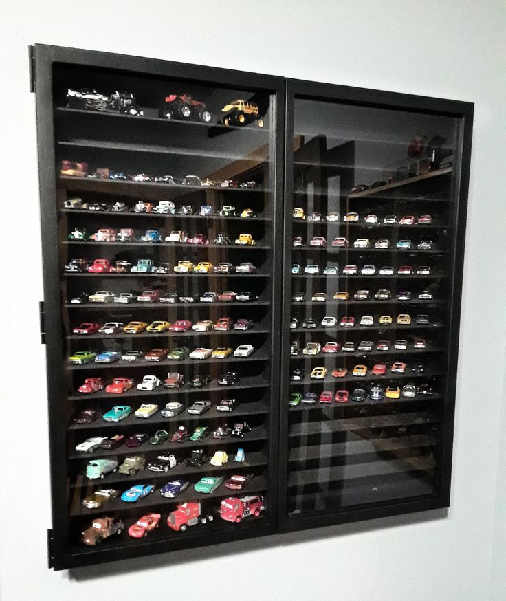 two glass doors that are open to show various toy cars in the display case on the wall