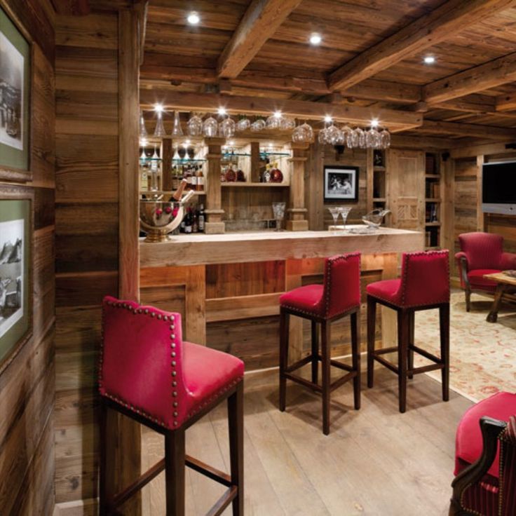 a bar with red chairs and wooden walls