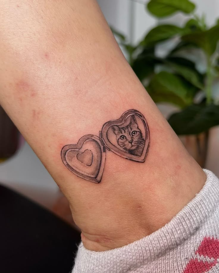 a cat in a heart shaped box tattoo on the wrist