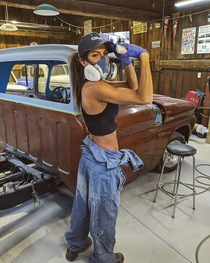 a woman is working on an old car in a garage with her hands on the hood