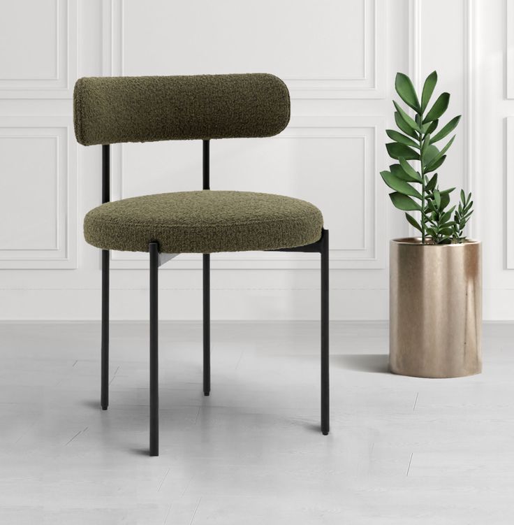 a green chair next to a potted plant in a room with white walls and flooring