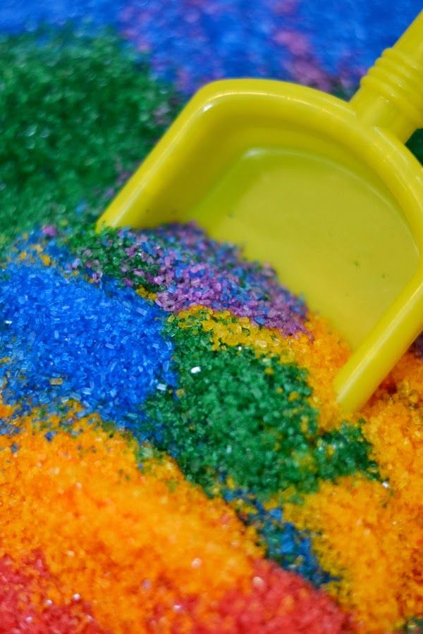 a yellow shovel sitting on top of a pile of colored sand