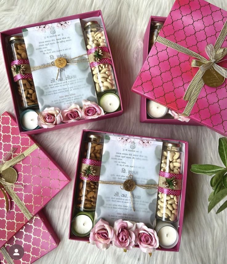 three pink boxes filled with candles and flowers on top of a white furnishing