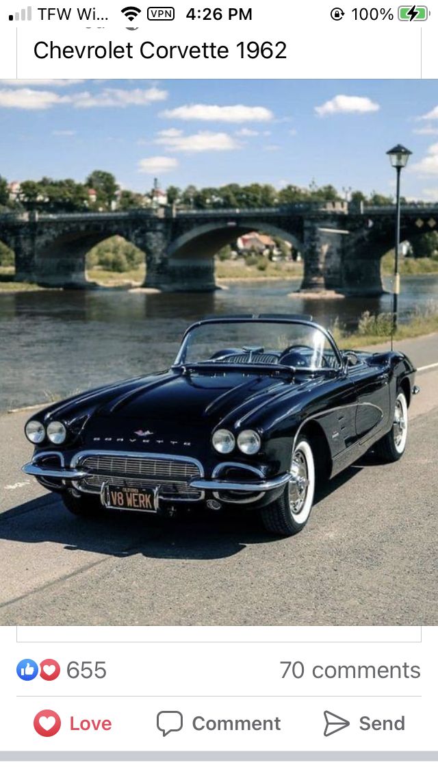 an old black car is parked on the side of the road next to a bridge