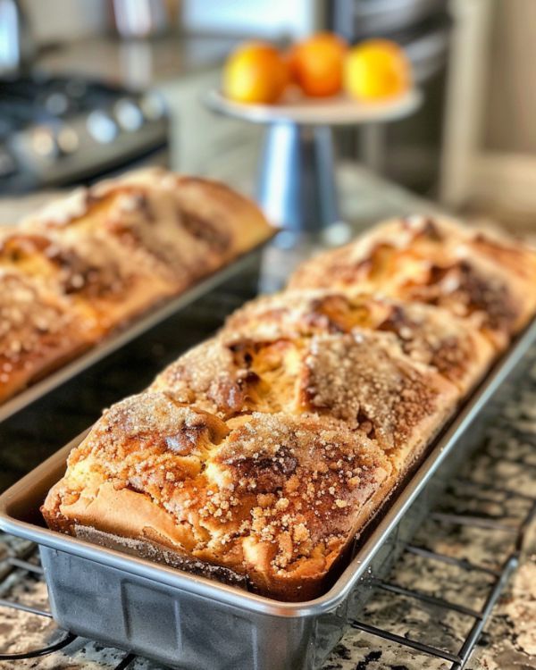 two loafs of bread sitting on top of a metal rack next to oranges