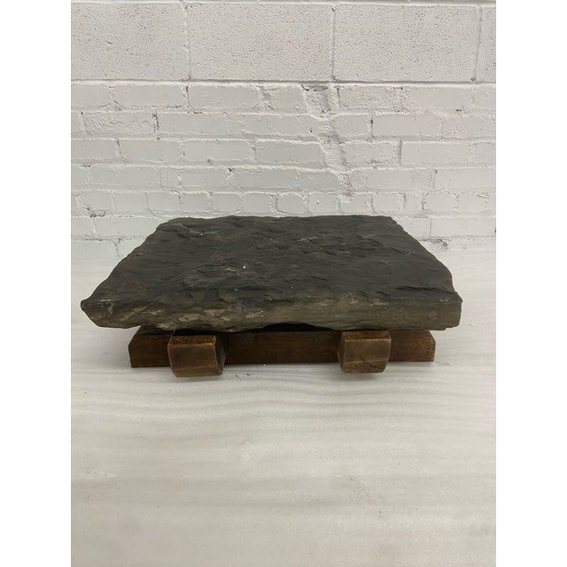 a black stone with two wooden legs on a white brick wall