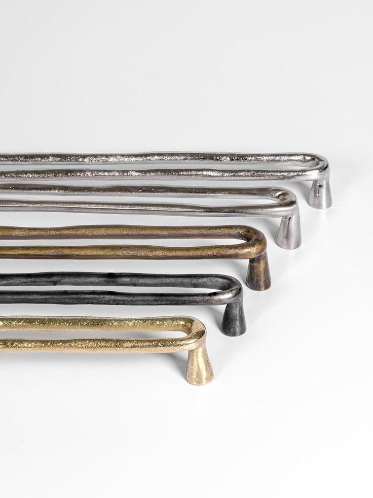 five different colored metal handles on a white surface, one is gold and the other is silver