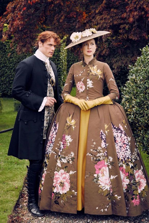 a man and woman dressed in period clothing standing next to each other on the grass