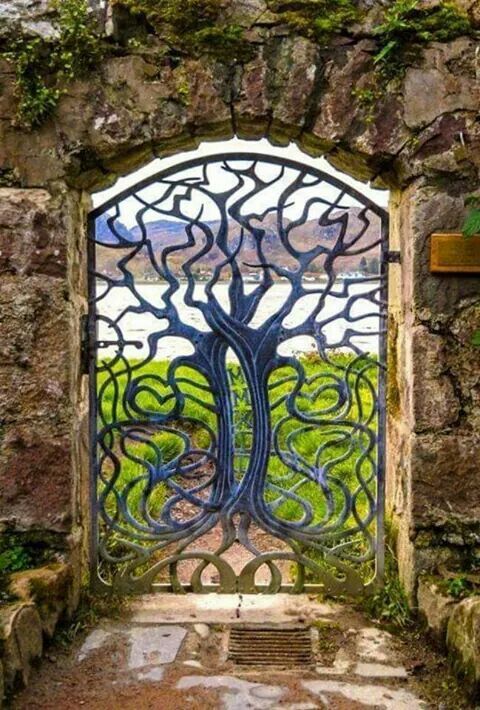 an iron gate with a tree in the center and vines growing out of it's sides