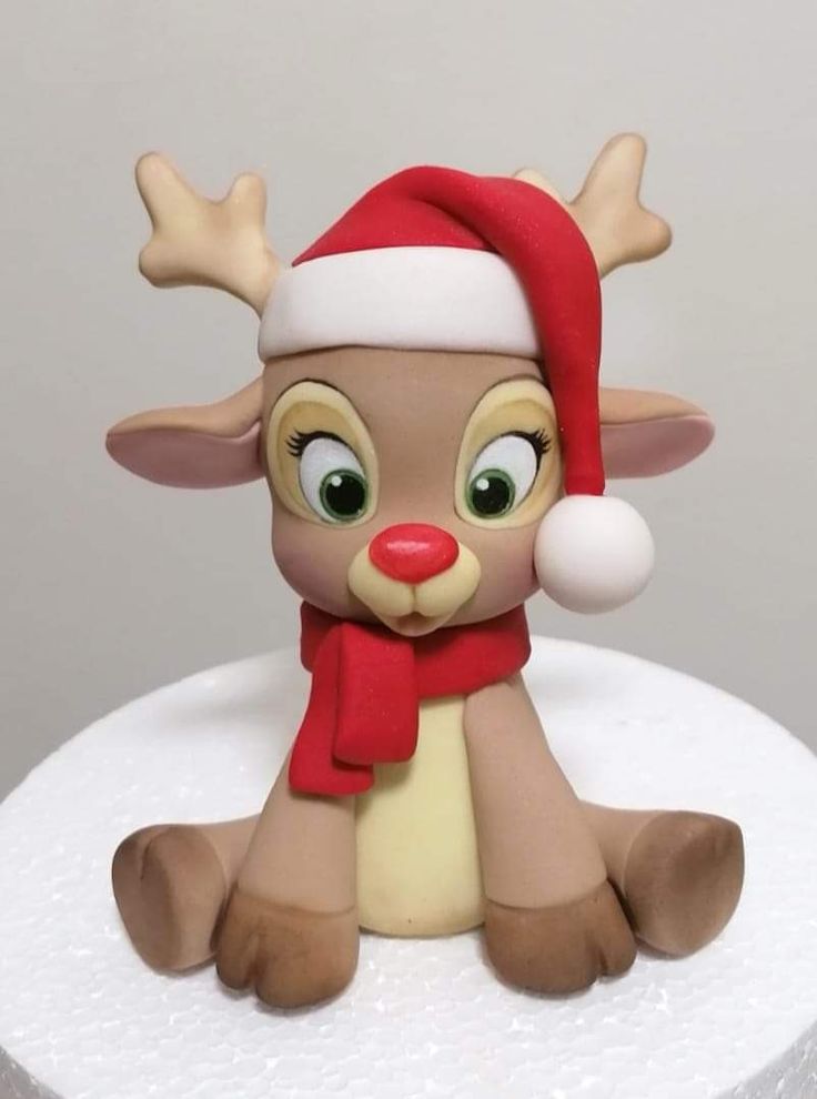 a close up of a cake with a toy reindeer on it's head and wearing a santa hat