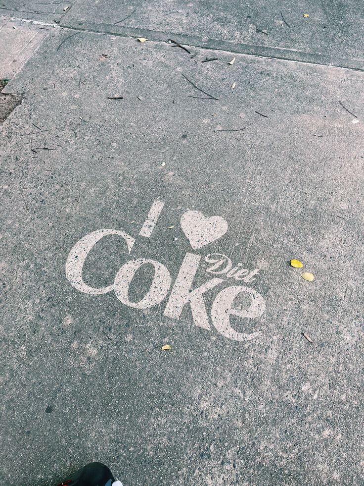 someone's feet are standing on the sidewalk near a chalk drawing that says i love coke