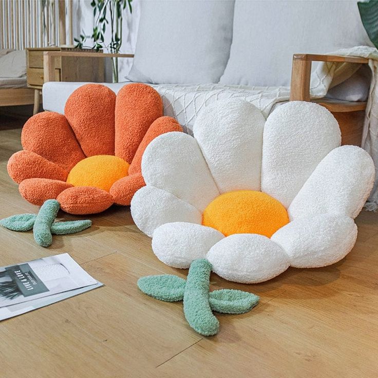 three decorative pillows sitting on top of a wooden floor next to a couch and chair