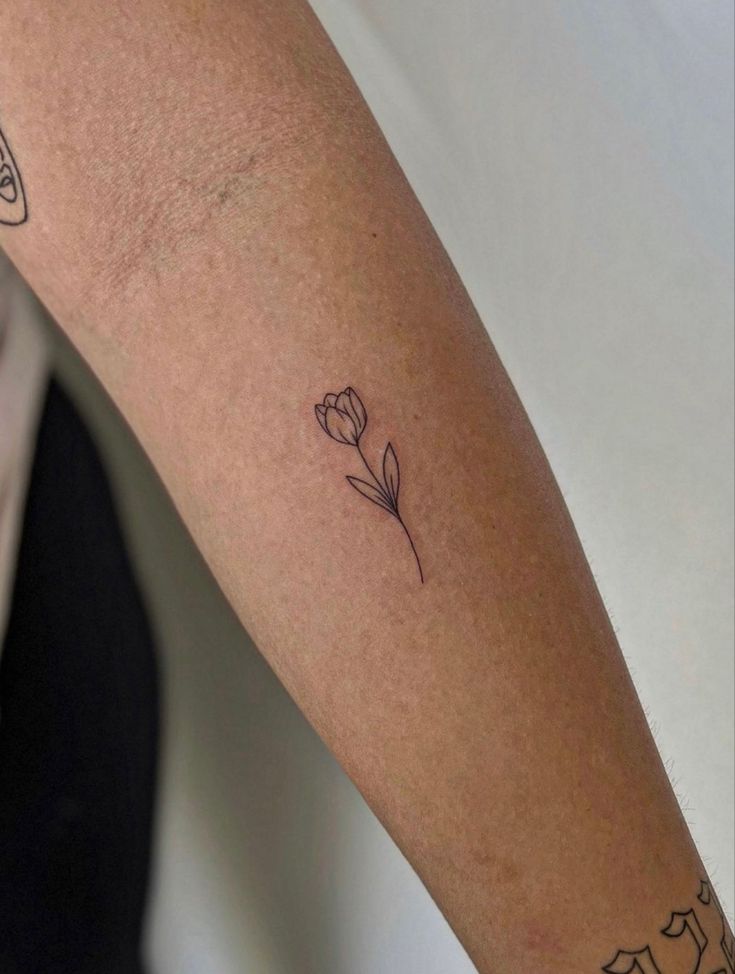 a woman's arm with a single flower tattoo on it