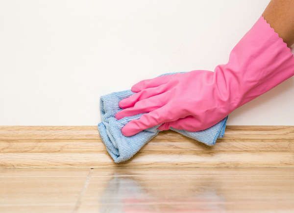 a person wearing pink gloves and holding a cleaning cloth