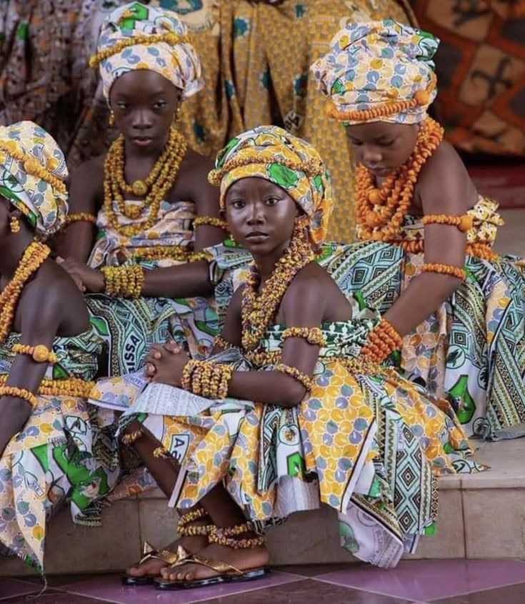 four women dressed in african clothing sitting on steps