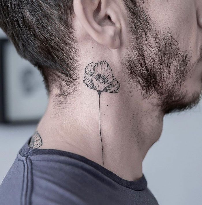 a man's neck with a flower tattoo on the back of his left ear