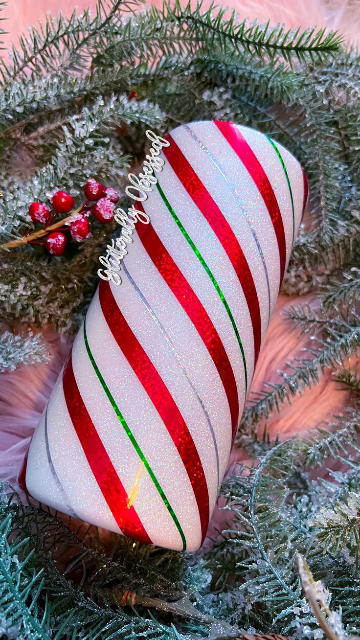 a christmas ornament with candy canes on top of it, surrounded by evergreen branches