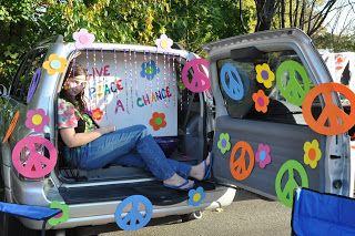 a woman sitting in the back of a truck decorated with peace signs