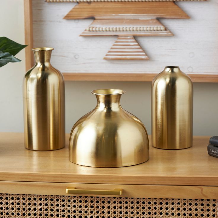 three gold vases sitting on top of a wooden table