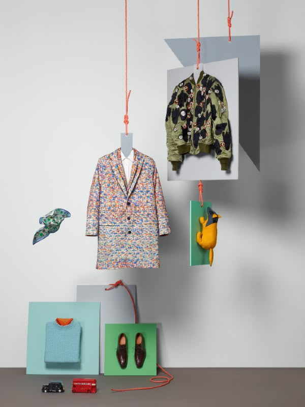 an assortment of clothing hanging from hooks on the wall next to shoes and toys in boxes